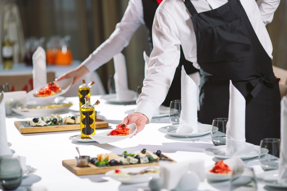 Serveur servant de table dans le restaurant s'apprête à recevoir des invités.
